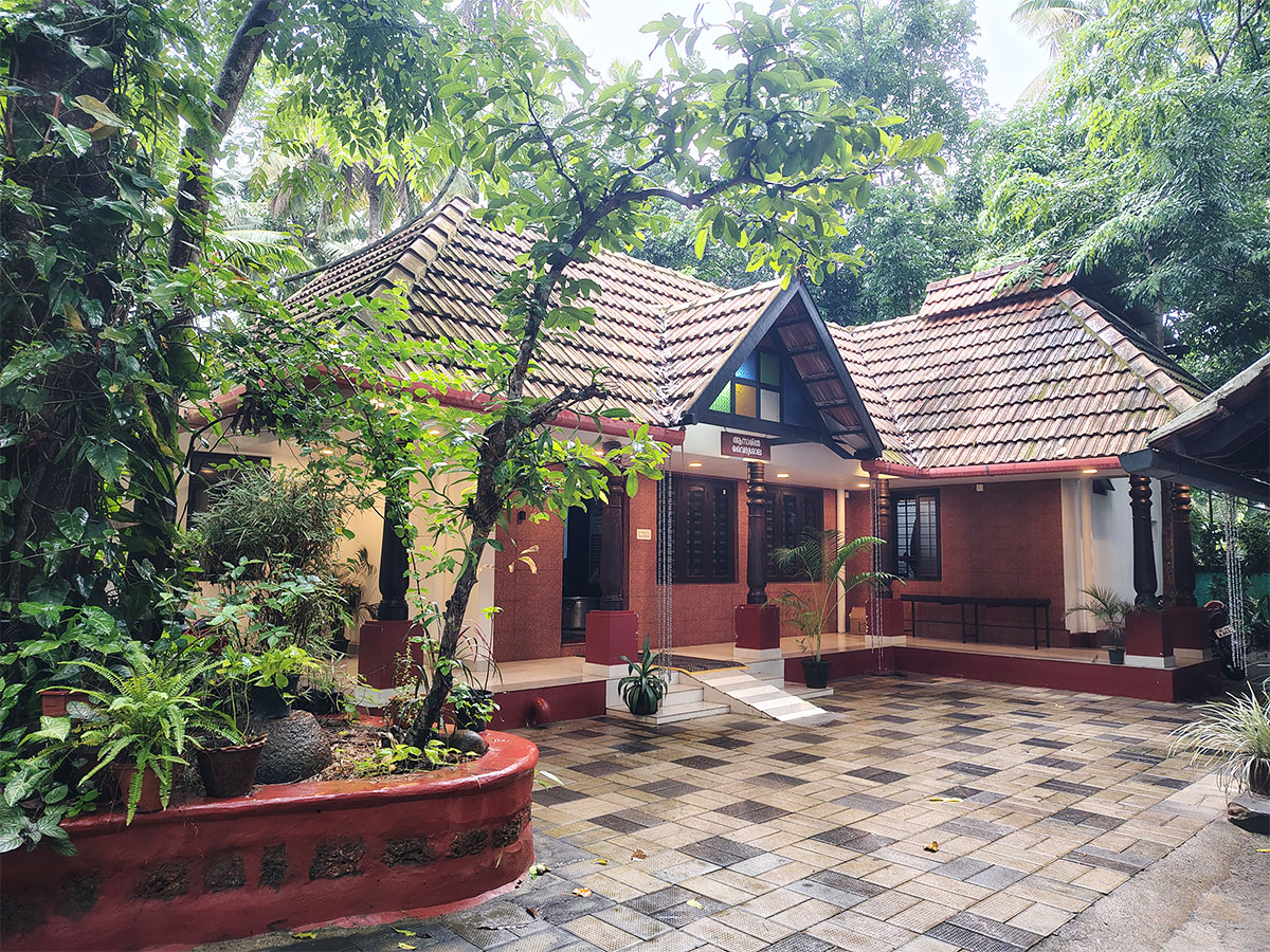 The clinic building, tiled roof and laterite walls, seen across the planted courtyard