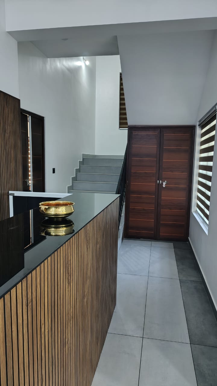 The reception counter in wood and stone, with a brass urli and the staircase beyond